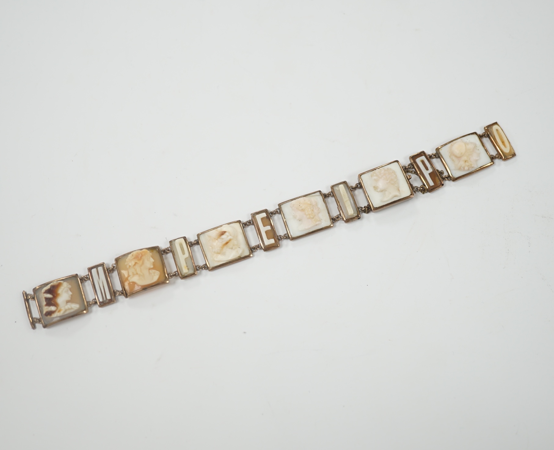 A 19th century Italian? yellow metal overlaid and cameo shell set bracelet, with panels of letters spelling 'Pompei' and panels of busts carved to dexter and sinister, (a.f.), overall 16.8cm.